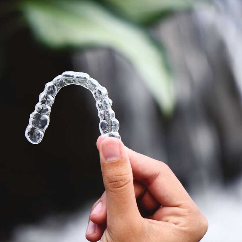 Transparente naturaligner®-Schiene zwischen zwei Fingern gehalten